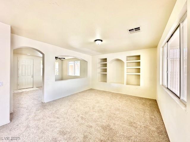 unfurnished room featuring light carpet and built in features