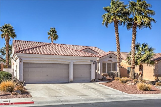 mediterranean / spanish-style house with a tile roof, an attached garage, concrete driveway, and stucco siding