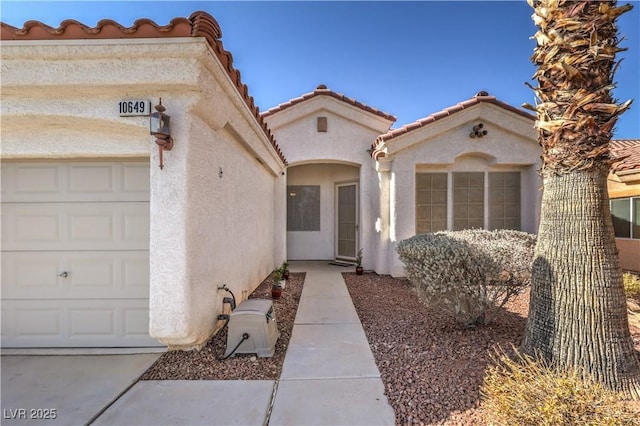 property entrance featuring a tile roof, a garage, and stucco siding