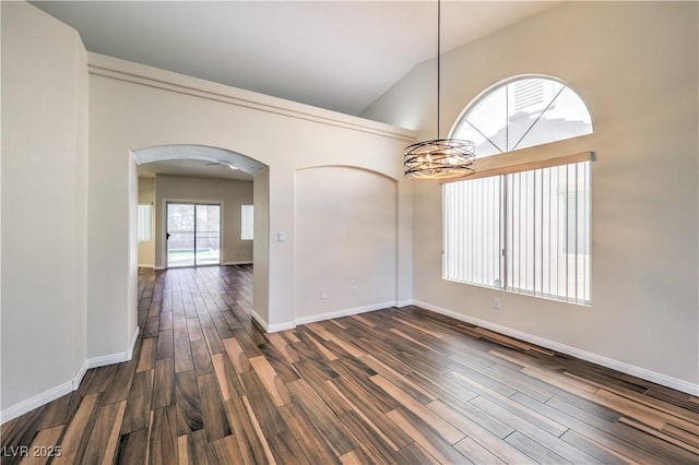 empty room with baseboards, lofted ceiling, arched walkways, dark wood-type flooring, and a notable chandelier