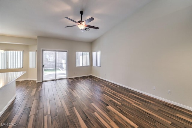 spare room featuring visible vents, ceiling fan, dark wood-type flooring, and baseboards