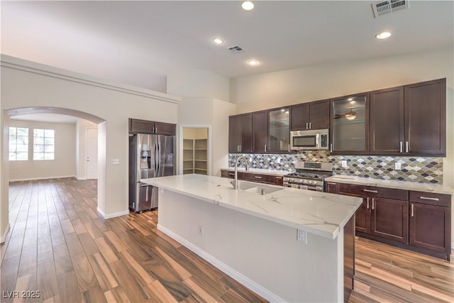 kitchen featuring tasteful backsplash, sink, hardwood / wood-style flooring, stainless steel appliances, and a center island with sink