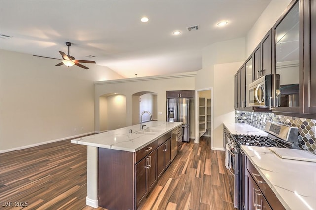 kitchen with dark wood-type flooring, appliances with stainless steel finishes, a kitchen island with sink, and sink