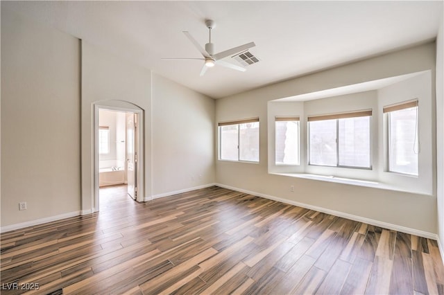 unfurnished room with vaulted ceiling, visible vents, baseboards, and wood finished floors