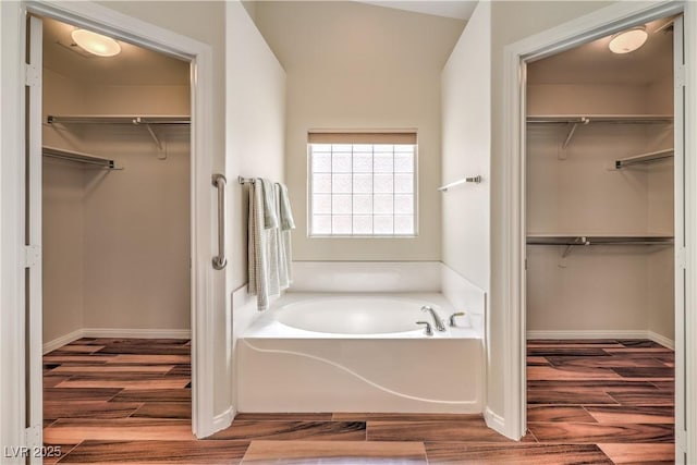 bathroom with a tub to relax in and wood-type flooring