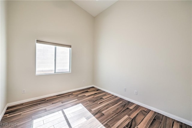 unfurnished room with baseboards, wood finish floors, and vaulted ceiling