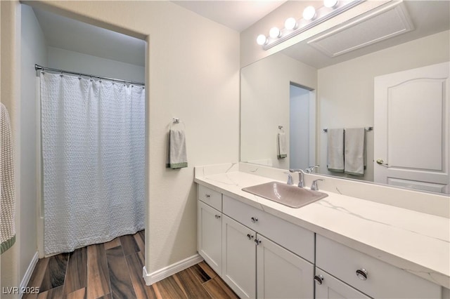 full bathroom featuring curtained shower, vanity, baseboards, and wood finished floors