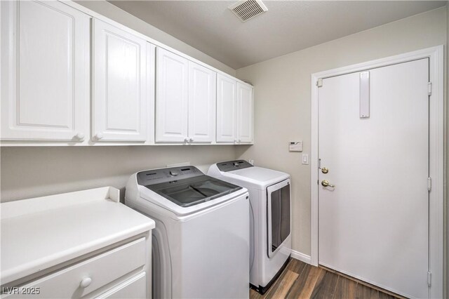 laundry room with washing machine and clothes dryer, visible vents, cabinet space, and dark wood-style flooring