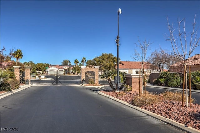 view of road with curbs, street lights, a gated entry, and a gate