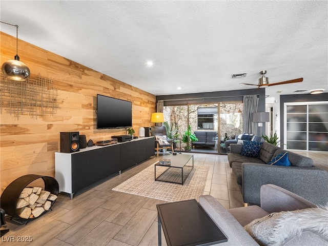 living room with wood-type flooring, wooden walls, and a textured ceiling