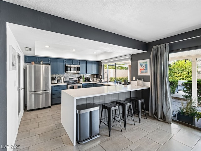 kitchen with stainless steel appliances, blue cabinets, a kitchen breakfast bar, and kitchen peninsula