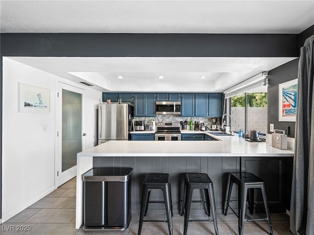 kitchen with blue cabinetry, a breakfast bar, sink, kitchen peninsula, and stainless steel appliances