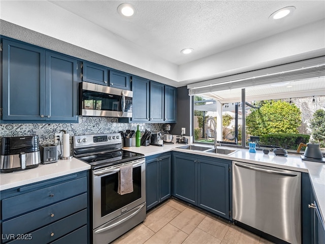 kitchen featuring blue cabinetry, sink, a textured ceiling, stainless steel appliances, and backsplash