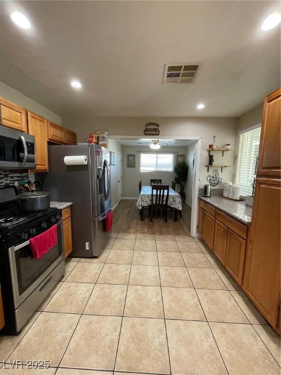 kitchen featuring a wealth of natural light, appliances with stainless steel finishes, light tile patterned floors, and ceiling fan