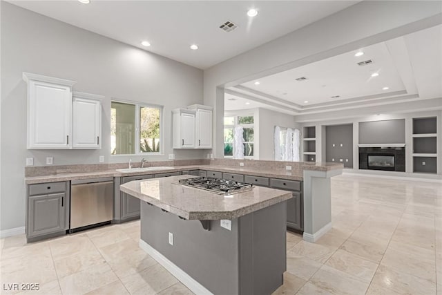 kitchen with gray cabinetry, white cabinetry, a center island, appliances with stainless steel finishes, and a kitchen breakfast bar