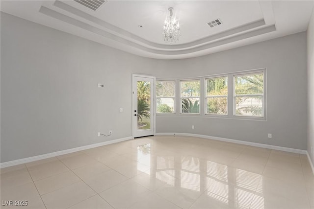 tiled spare room with a wealth of natural light, an inviting chandelier, and a tray ceiling