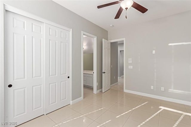 unfurnished bedroom featuring ensuite bathroom, a closet, ceiling fan, and light tile patterned flooring