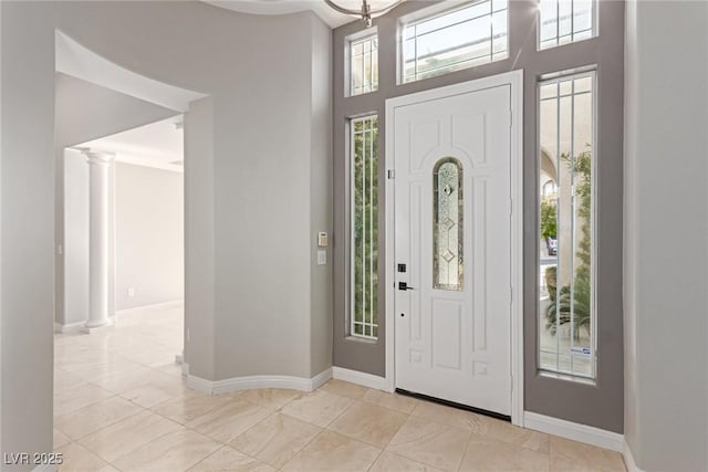 foyer entrance with a wealth of natural light, a high ceiling, and ornate columns