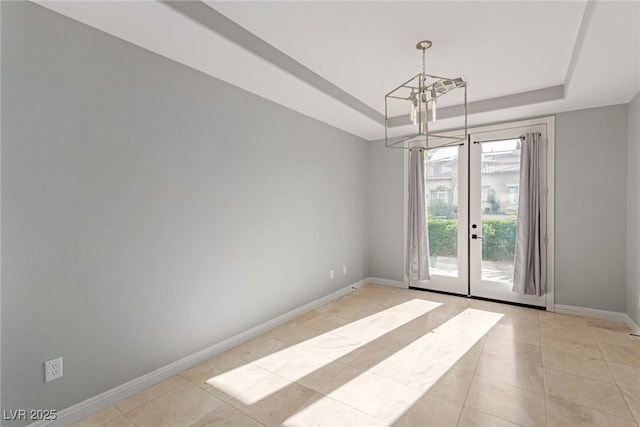 tiled empty room with a raised ceiling and a notable chandelier