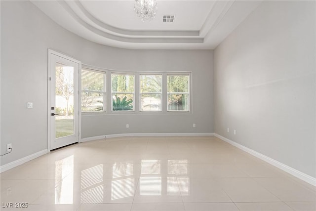 unfurnished room with an inviting chandelier, light tile patterned floors, and a tray ceiling