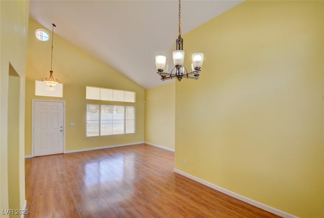 unfurnished room with high vaulted ceiling, a chandelier, and light hardwood / wood-style floors