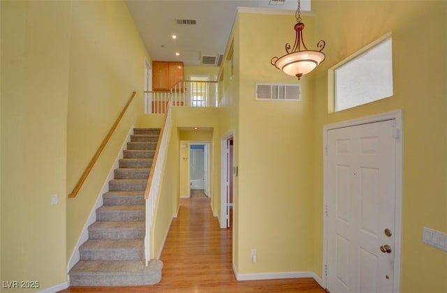 foyer entrance featuring a towering ceiling and light wood-type flooring