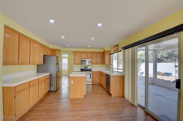 kitchen featuring sink, light hardwood / wood-style flooring, appliances with stainless steel finishes, a center island, and light brown cabinets