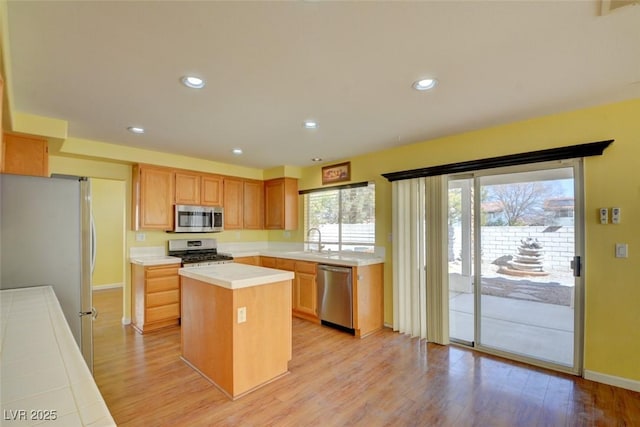 kitchen featuring appliances with stainless steel finishes, sink, a kitchen island, and light hardwood / wood-style flooring