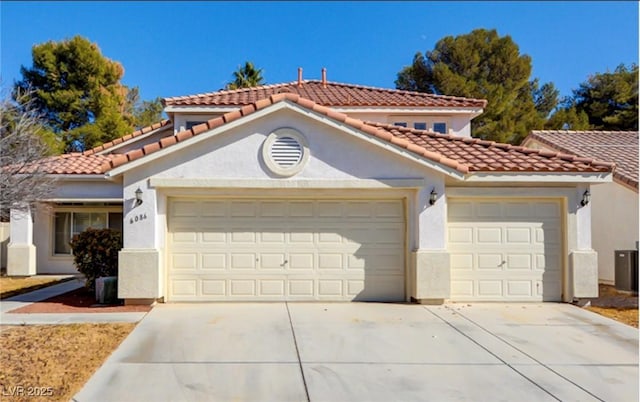 mediterranean / spanish-style house with an attached garage, a tiled roof, concrete driveway, and stucco siding