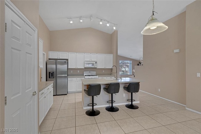 kitchen featuring sink, white cabinets, hanging light fixtures, light tile patterned floors, and white appliances