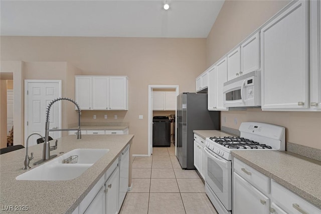 kitchen with sink, white appliances, light tile patterned floors, white cabinetry, and washer / dryer