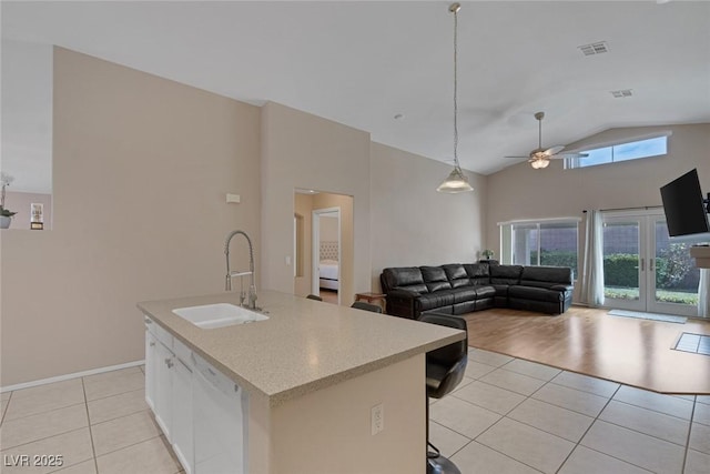 kitchen with light tile patterned flooring, sink, a kitchen breakfast bar, dishwasher, and an island with sink