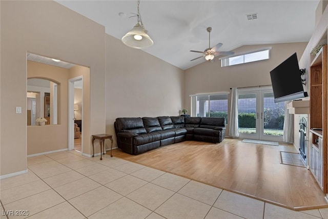 tiled living room with high vaulted ceiling, ceiling fan, and french doors