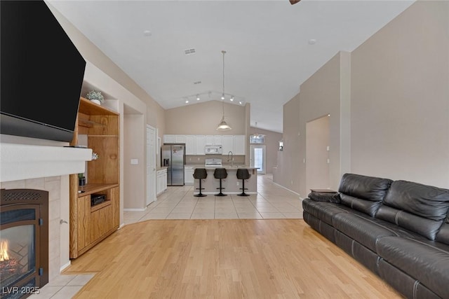 living room with lofted ceiling, a fireplace, light hardwood / wood-style floors, and sink