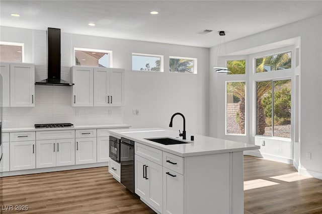 kitchen featuring white cabinetry, pendant lighting, sink, and wall chimney range hood