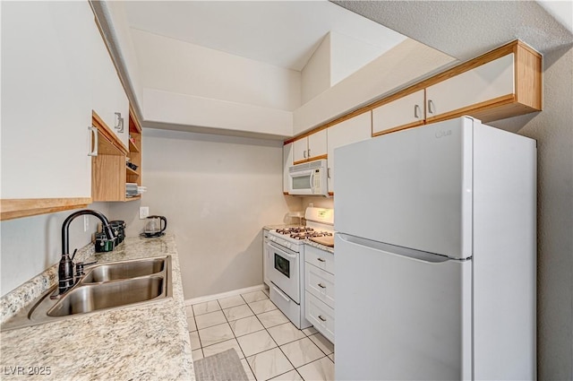 kitchen with light tile patterned flooring, built in desk, white cabinetry, sink, and white appliances