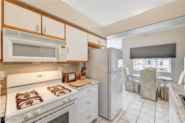 kitchen featuring white cabinetry, white appliances, and light stone countertops