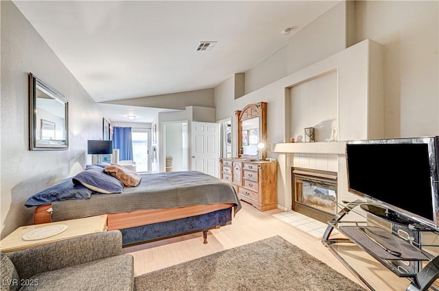 bedroom featuring lofted ceiling, a fireplace, and light hardwood / wood-style flooring