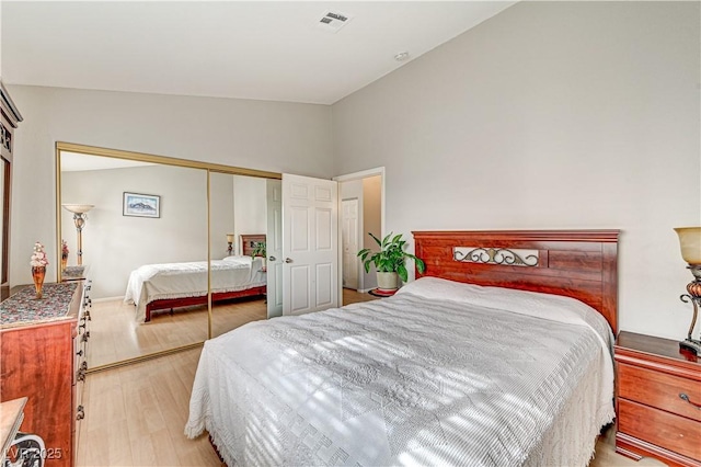 bedroom featuring vaulted ceiling, light hardwood / wood-style floors, and a closet