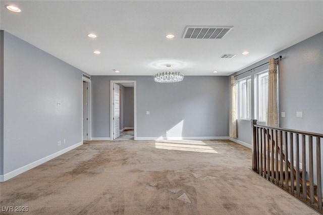 carpeted empty room with a notable chandelier