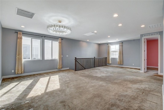 empty room with light colored carpet and a chandelier