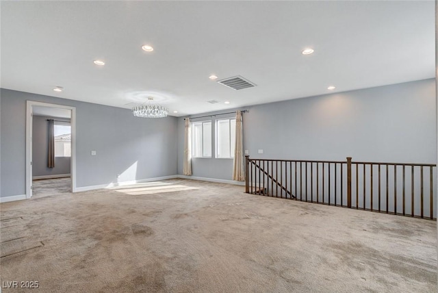 empty room featuring an inviting chandelier, plenty of natural light, and light carpet