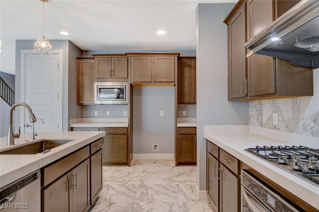 kitchen with extractor fan, appliances with stainless steel finishes, decorative light fixtures, sink, and backsplash