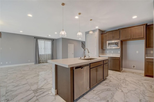 kitchen featuring stainless steel appliances, sink, a kitchen island with sink, and hanging light fixtures