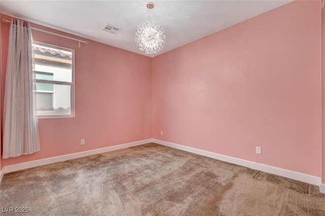 spare room featuring carpet flooring and a notable chandelier