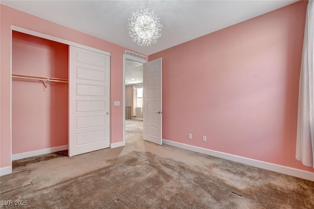 unfurnished bedroom with a notable chandelier, a closet, and carpet