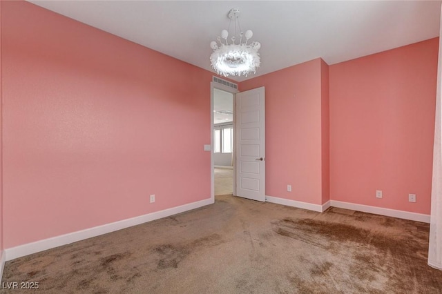 carpeted spare room featuring a chandelier