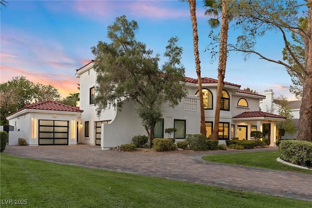 mediterranean / spanish-style home with a yard and a garage