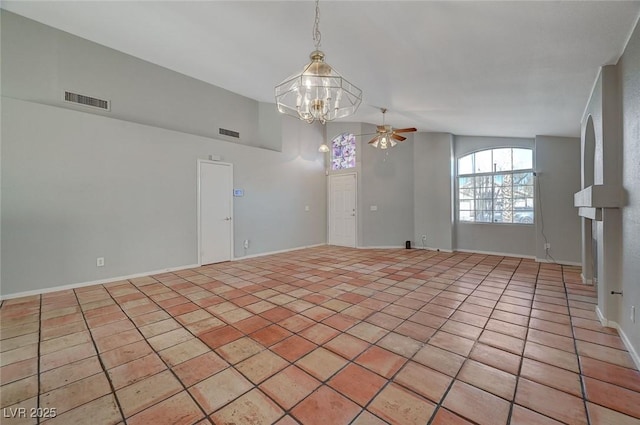 spare room with ceiling fan with notable chandelier and light tile patterned floors