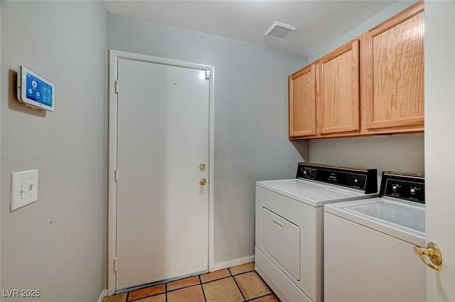 clothes washing area featuring cabinets, washing machine and dryer, and light tile patterned floors